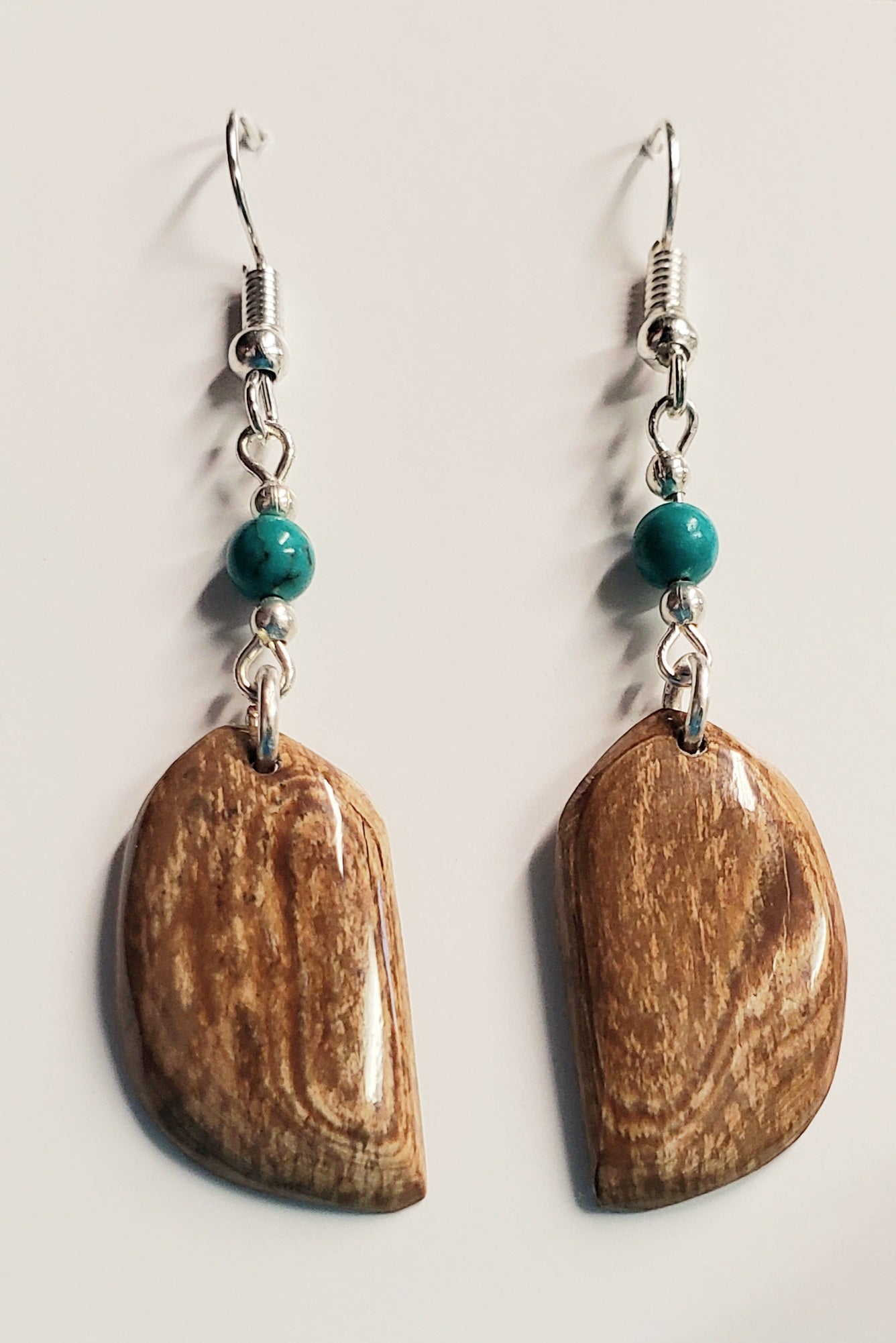 These long Feather shaped earrings are hand crafted from Fossil Mammoth Ivory found in Canada. The Ivory is about 35,000 years old and is all naturally colored just the way it came out of the ground. This highlighted with Howlite Turquoise beads.
Hung on Stainless steel earrings.